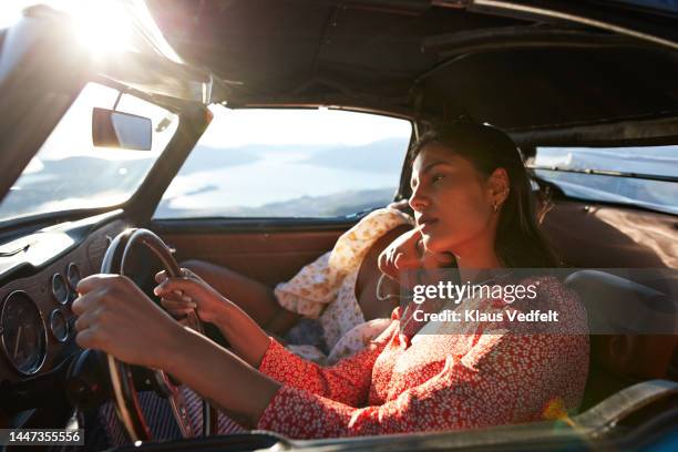 young woman driving by tired friend in car - auto schlafen stock-fotos und bilder
