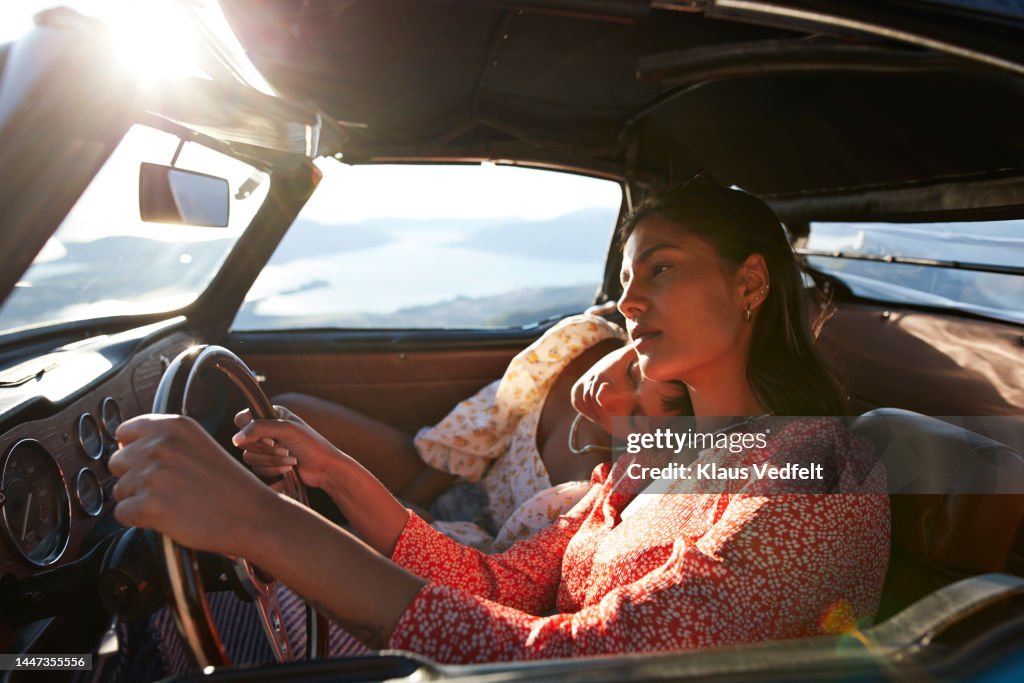 Young woman driving by tired friend in car