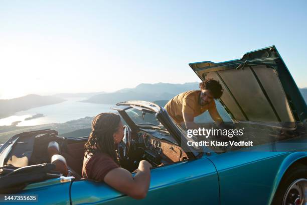 man talking with girlfriend while repairing car - car top view photos et images de collection