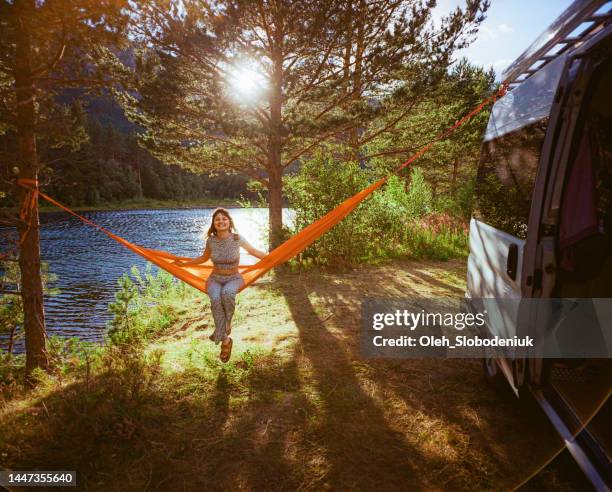 woman resting in hammock near camper van in forest - archival camping stock pictures, royalty-free photos & images