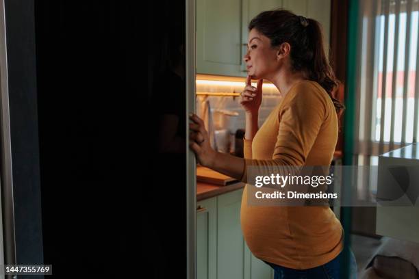 pregnant woman looking for food in fridge. - mom fridge stock pictures, royalty-free photos & images