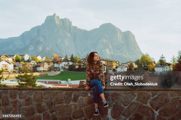 woman sitting on the background of village in dolomites - vista posterior stock pictures, royalty-free photos & images