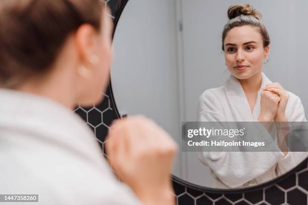 young woman looking at bathroom mirror. - bathroom mirror 個照片及圖片檔