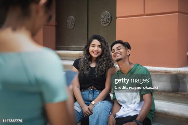 young couple of university students being photographed at the campus - focus on background bildbanksfoton och bilder