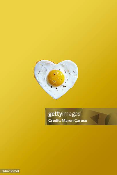 heart shaped fried egg on yellow background - creative food stock pictures, royalty-free photos & images