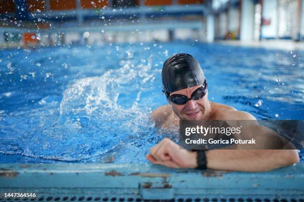 young man checking his heart rate on a smartwatch before swimming in the swimming pool - swimming goggles stock pictures, royalty-free photos & images