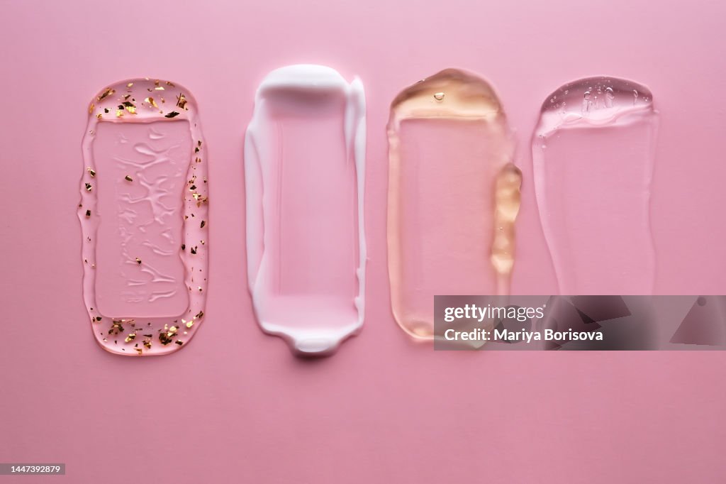 Textures of different cosmetics on a pink background.