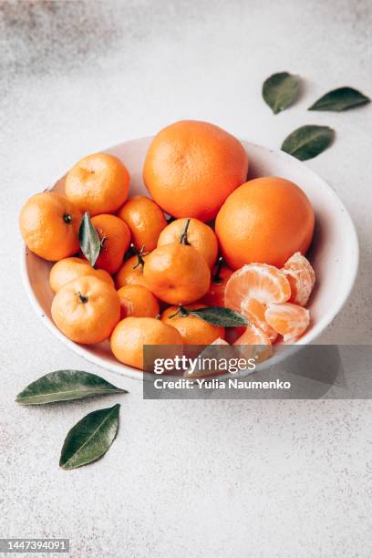 fresh tangerines with green leaves in a bowl. - mandarine stock pictures, royalty-free photos & images