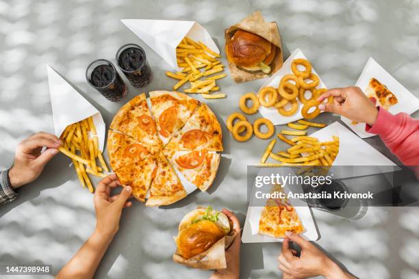 human hands with assorted take out food such as pizza, french fries, onion rings, burger and cola. - snabbmat bildbanksfoton och bilder
