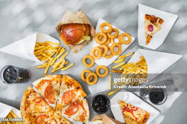 assorted take out food such as pizza, french fries, onion rings, burger and cola. - essen in fertigpackung stock-fotos und bilder