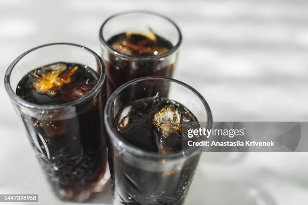 cold refreshing dark cola with ice cubes on a gray background. - coke stock-fotos und bilder