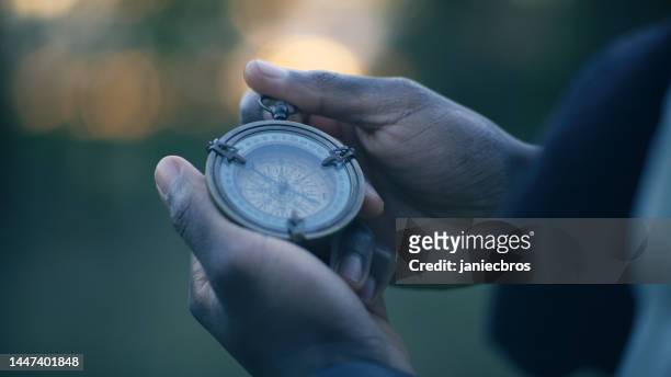 african ethnicity person holding a compass. planning trip and checking directions - kompas stockfoto's en -beelden