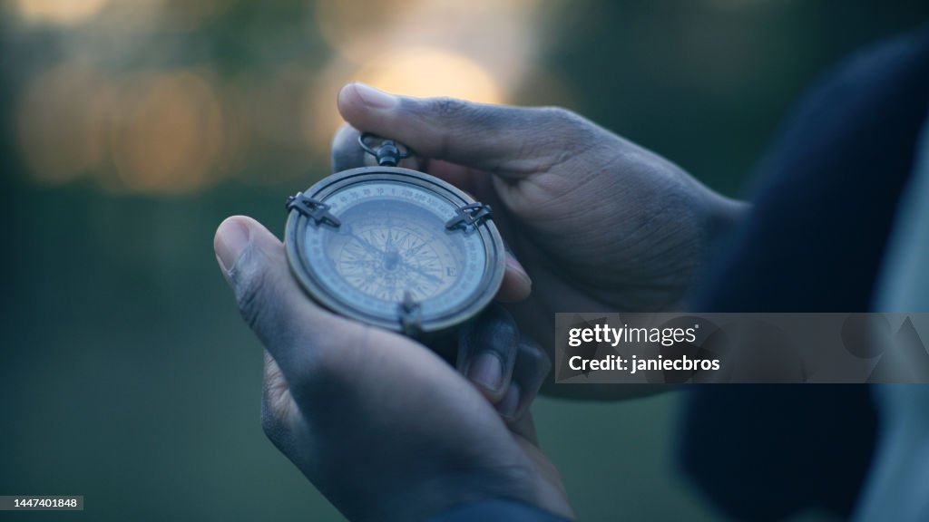 African ethnicity person holding a compass. Planning trip and checking directions