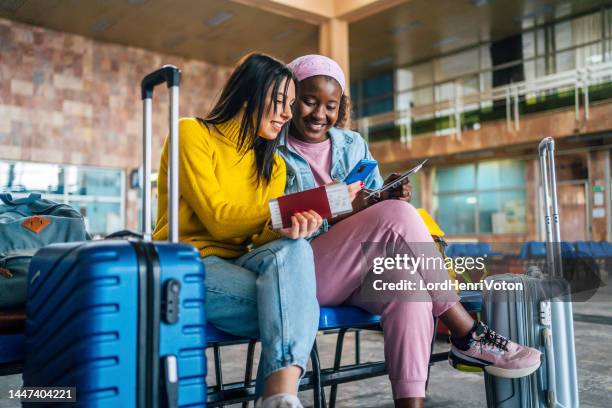 girlfriends using mobile phone at the airport - holiday travel ahead of thanksgiving clogs airports highways and train stations stockfoto's en -beelden