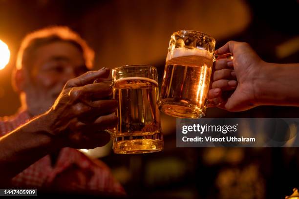 senior man clinking beer glasses at the pub. - craft beer festival stock pictures, royalty-free photos & images