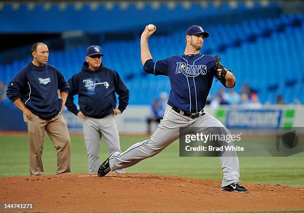 Jeff Niemann of the Tampa Bay Rays delivers a pitch as Head Athletic Therapist Ron Porterfield and Manager Joe Maddon look on during a break in MLB...