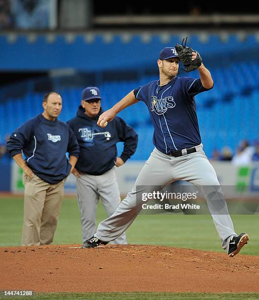 Jeff Niemann of the Tampa Bay Rays delivers a pitch as Head Athletic Therapist Ron Porterfield and Manager Joe Maddon look on during a break in MLB...