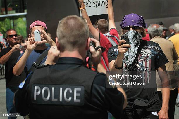 Using cameras a police officer squares off with protestors during a demonstration organized by National Nurses United in Daley Plaza where they were...