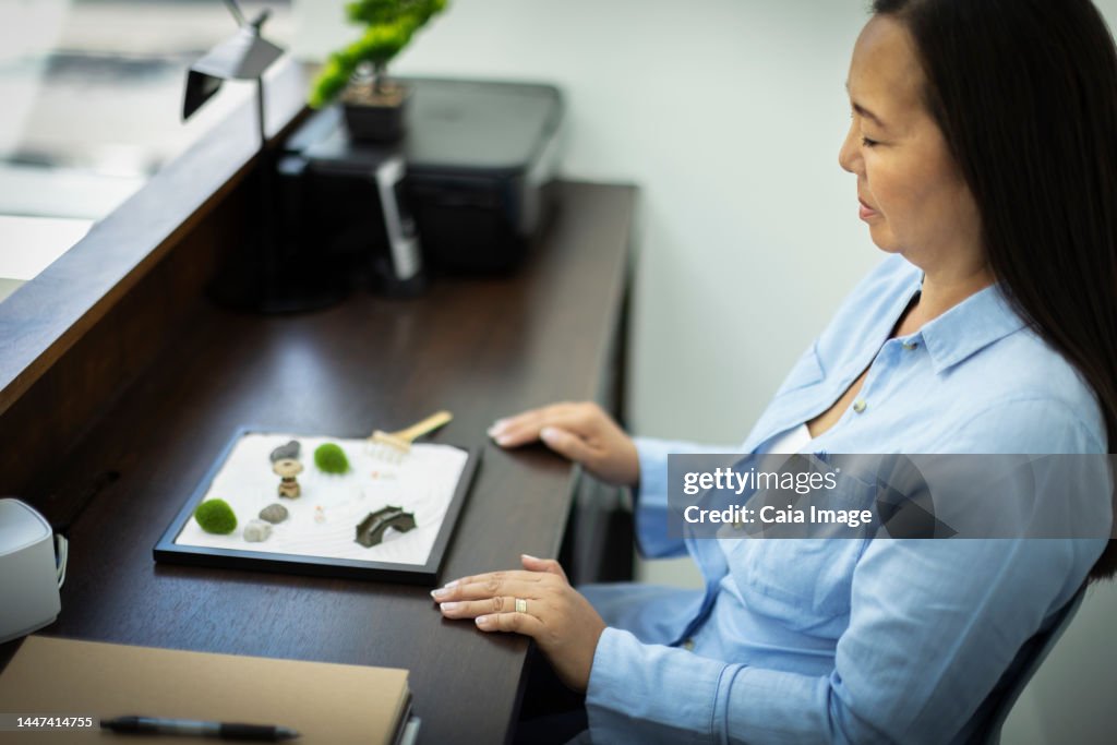 Businesswoman taking a break at mini zen garden