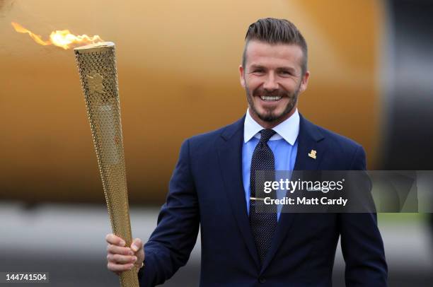 David Beckham holds the Olympic Flame as it arrives at RNAS Culdrose near Helston on May 18, 2012 in Cornwall, England. The Olympic Flame arrived in...