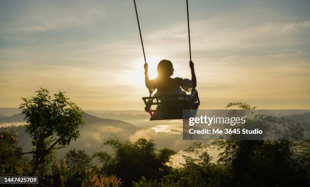 a woman on a rope swing in mountains thailand. - schaukel stock-fotos und bilder