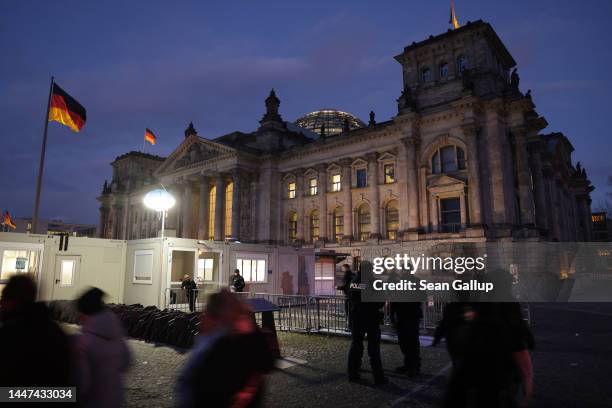 Police and visitors stand outside the Reichstag, seat of the Bundestag, Germany's parliament, at dusk on the day police conducted nationwide raids...