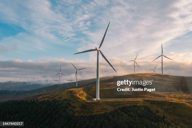a sunset drone view of a wind farm on a hilltop in scotland - windenergie stock-fotos und bilder