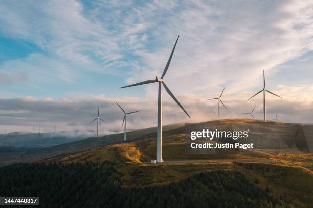 a sunset drone view of a wind farm on a hilltop in scotland - producción de combustible y energía fotografías e imágenes de stock