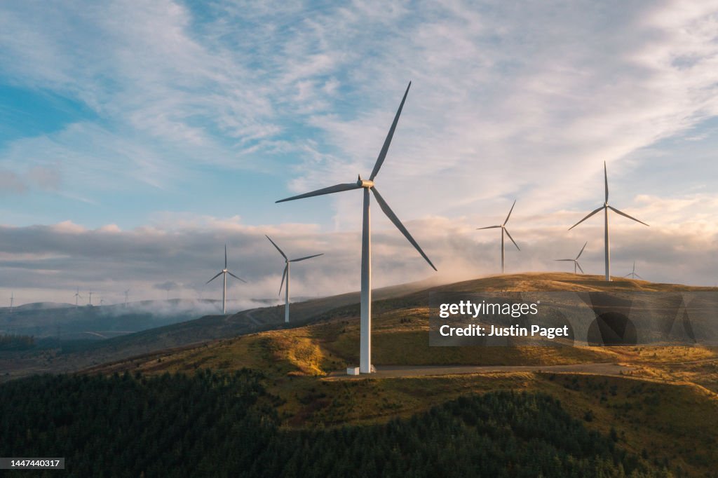 A sunset drone view of a wind farm on a hilltop in Scotland