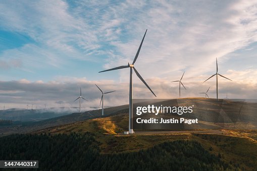 A sunset drone view of a wind farm on a hilltop in Scotland A sunset drone view of a wind farm on a hilltop in Scotland