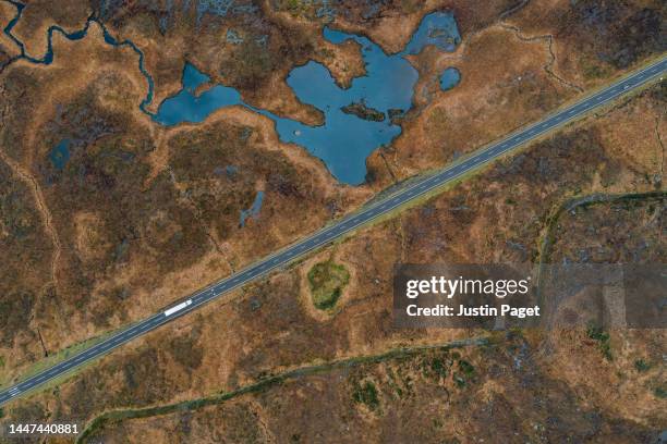 drone view down onto a white lorry transporting goods in the scottish highlands - highlands stock-fotos und bilder