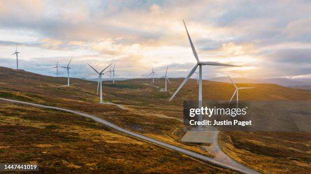 drone view of a hilltop wind farm close to sunset in scotland - wind power stock pictures, royalty-free photos & images