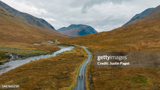two adventure cyclists on a single track road in the scottish highlands on a winters day - glen etive photos et images de collection