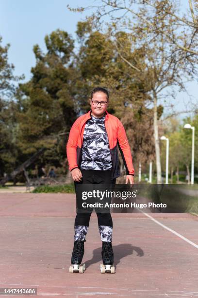 blonde girl with eyeglasses roller skating on a park - pasatiempos 個照片及圖片檔