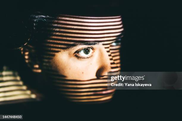 young woman is hiding, peeking out of the door hole - victim foto e immagini stock