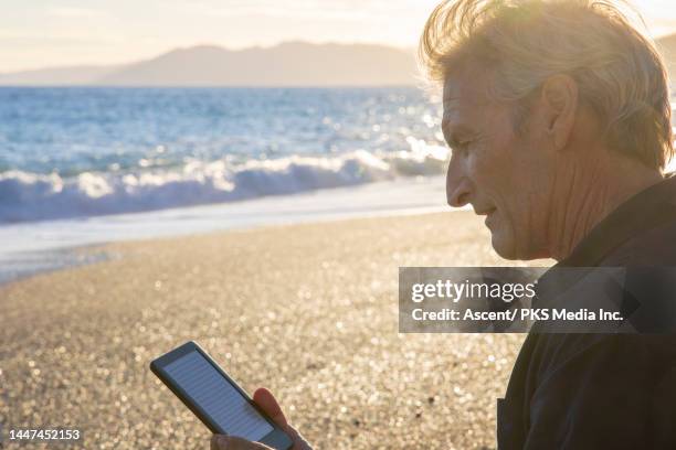 man uses digital reader on beach at sunset in autumn - imagem em movimento - fotografias e filmes do acervo