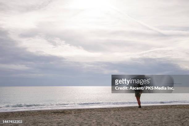 senior woman walks on beach with phone - profileren stockfoto's en -beelden