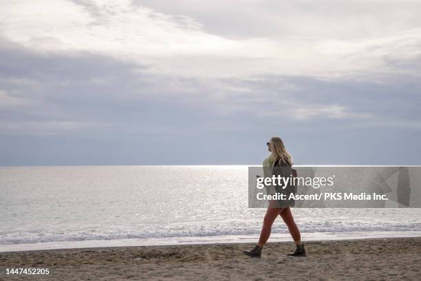 senior woman walks on beach with phone - imagem em movimento - fotografias e filmes do acervo