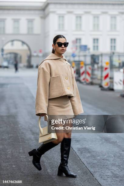 Bella Emaron wears beige Pataou jacket and skirt, vagabonds boots, Ysl sunglasses, white Jacquemus bag December 06, 2022 in Berlin, Germany.