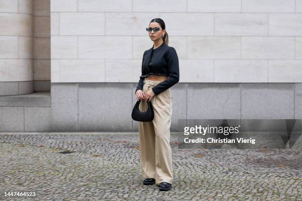 Bella Emar wears black Coperni cropped jacket , Coperni bag, Balenciaga sunglasses, Prada shoes, beige pants By Malene Birger on December 06, 2022 in...