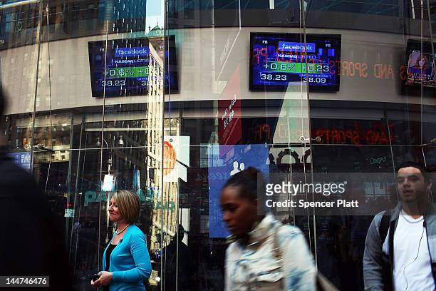 People walk by the Nasdaq stock market where a television monitor displays the newly debuted Facebook stock price at the end of the trading day on...