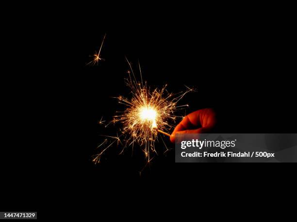 cropped hand holding sparkler against black background,sweden - helgdag stock-fotos und bilder