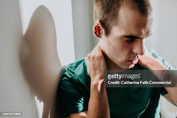 conceptual image of a man holding his neck, either in physical or emotional pain - head and shoulders fotografías e imágenes de stock