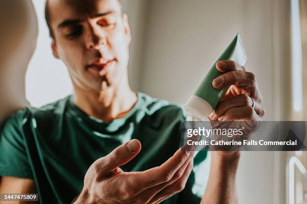 a man applies lotion to his hand - cosmética foto e immagini stock