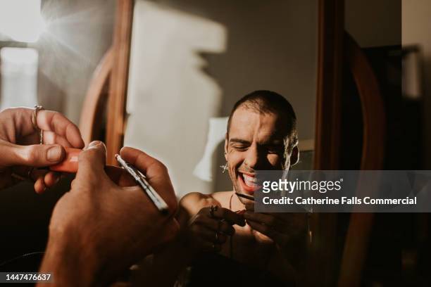 a confident. happy man applies make-up in a mirror - weight gain foto e immagini stock