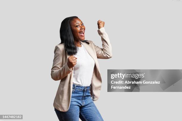 african woman laughing while raising her fist in celebration. - black awards stock pictures, royalty-free photos & images