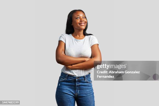 dreamy african woman looking up with her arms crossed - black pants stockfoto's en -beelden