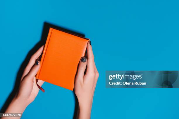 woman hands hold orange diary on bright desk - picture magazine stockfoto's en -beelden