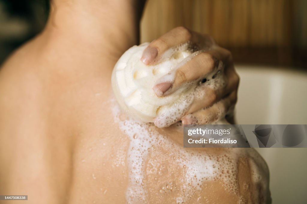 Loofah sponge with shower foam for washing the body in female hands. Relaxation and beauty treatments. Natural beauty, daily skincare routine. Moisturizing, cleansing