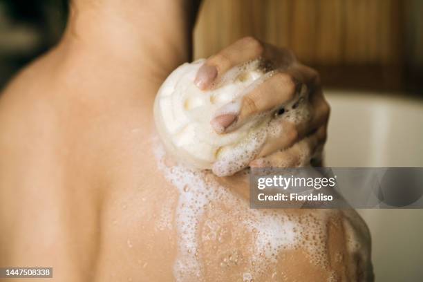 loofah sponge with shower foam for washing the body in female hands. relaxation and beauty treatments. natural beauty, daily skincare routine. moisturizing, cleansing - sabão imagens e fotografias de stock